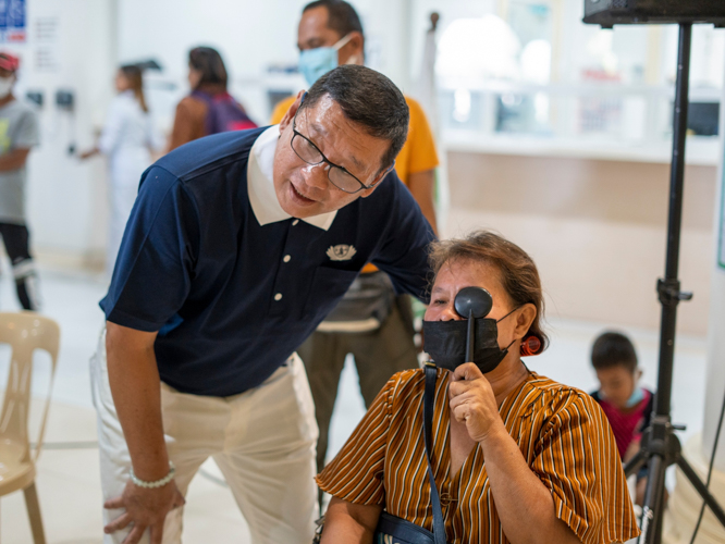 Tzu Chi Zamboanga Liaison Officer Dr. Anton Lim assists a patient in a visual acuity test. 【Photo by Harold Alzaga】