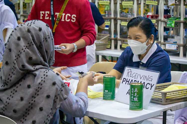 Tzu Chi volunteer and pharmacy head Rosa So (right) gladly hands over Minda Ramos’ medicines. 【Photo by Marella Saldonido】