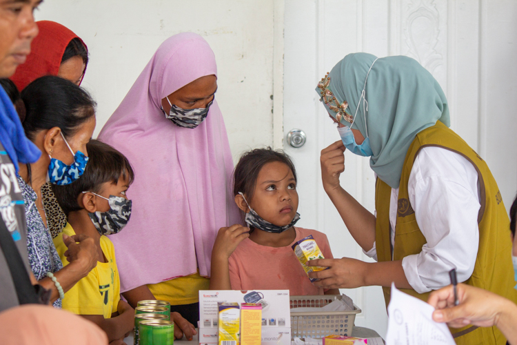 Bailanie Palakasi (in pink) and her children listen as a Tzu Chi volunteer explains how to take a supplement. 【Photo by Marella Saldonido】