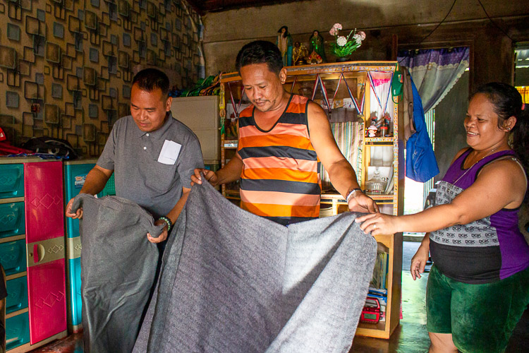 The husband of Emma Solis (center) proudly shows the blanket given by Tzu Chi, which they have safely kept for 10 years. 【Photo by Marella Saldonido】