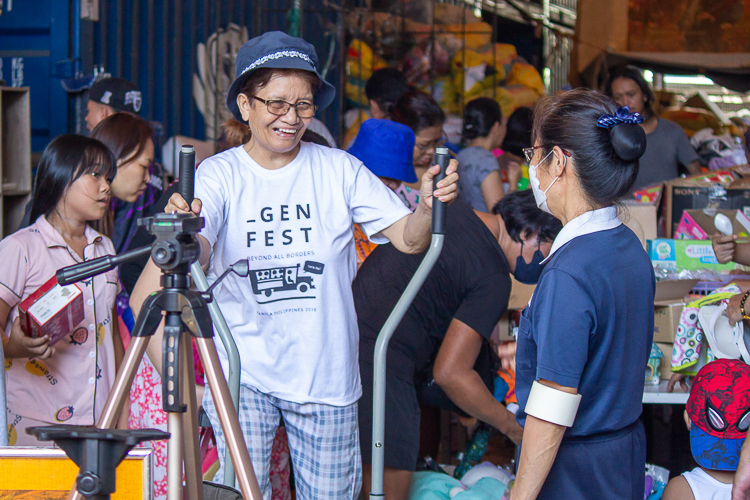 A customer enthusiastically tries out an exercise machine displayed amongst miscellaneous items for sale such as camera tripods, home decorations, children’s toys, and more. 【Photo by Marella Saldonido】