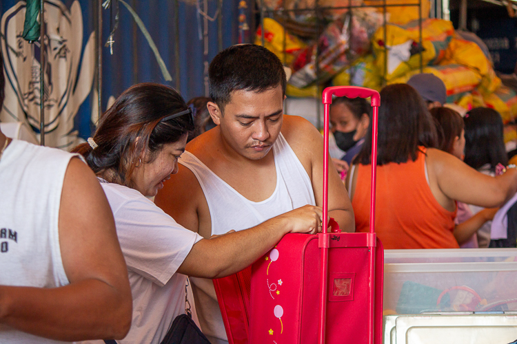 Two customers carefully check the condition of the trolley bag. 【Photo by Marella Saldonido】