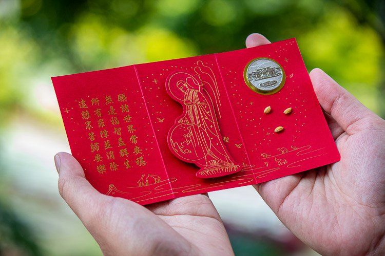 Attendees of the Typhoon Yolanda 10th Year Remembrance Mass at the Sto. Niño Church in Tacloban individually receive a red envelope (angpao) blessed by Tzu Chi founder Dharma Master Cheng Yen, which contains a commemorative Tzu Chi coin and three grains of rice symbolizing discipline, determination, and wisdom. 【Photo by Marella Saldonido】