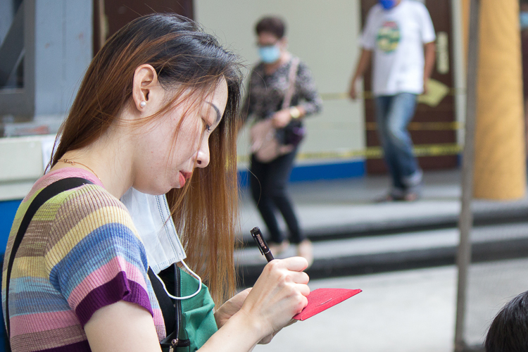 Liu Fang writes on the angpao containing their donation before handing it to Tzu Chi volunteers.【Photo by Marella Saldonido】