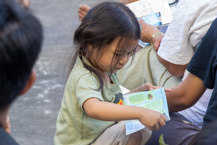A little girl goes over a pamphlet of Jing Si Aphorisms. 【Photo by Matt Serrano】