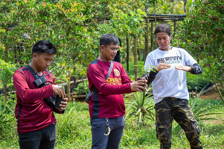 FEED Partnerships Director Anne Bakker (in white) and two forest rangers demonstrate how to properly pot new seedlings in the plant nursery. 【Photo by Marella Saldonido】