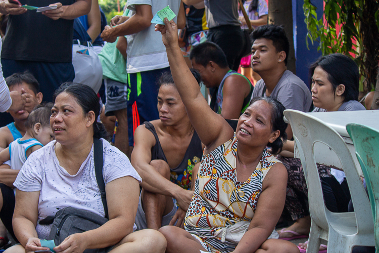 Enrica Allam, a beneficiary of the fire relief, waves her relief goods stubs in the air before distribution. 【Photo by Marella Saldonido】