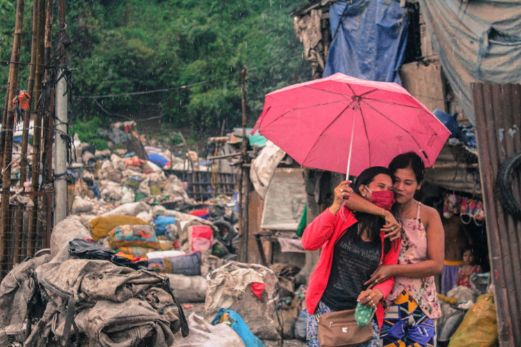 Roselyn de los Reyes (right) hugs Mylene Romano in gratitude for sharing her rice and relief goods. 【Photo by Matt Serrano】