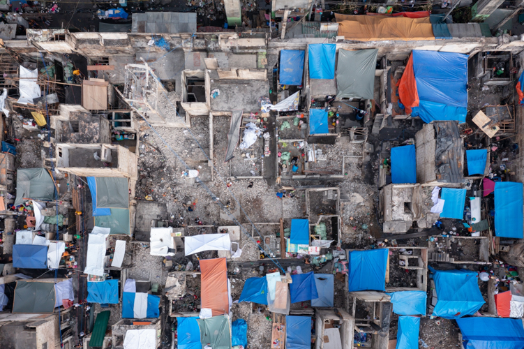 A drone shot of the fire scene shows that residents have used tarpaulin as temporary roofing for their burned homes.【Photo by Daniel Lazar】