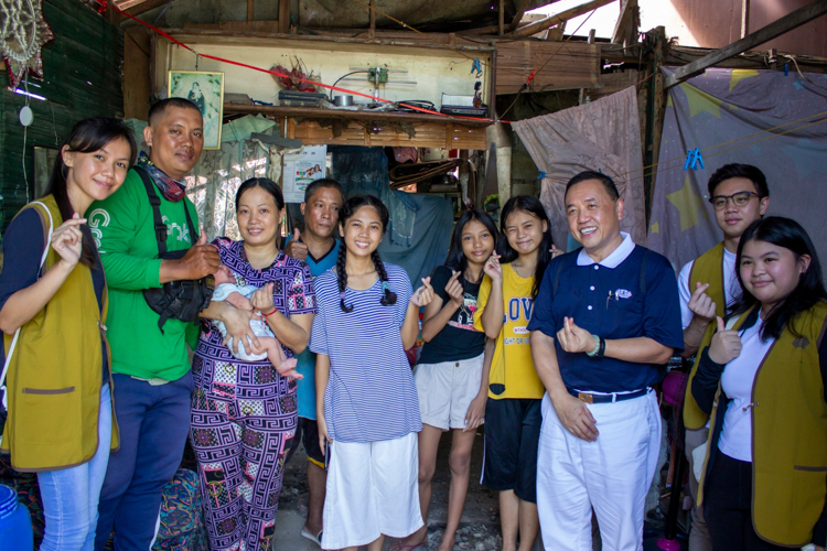 Daniella Diane Simran (in stripes) poses with her Grab deliver rider uncle Joeward (second from left), his family, and Tzu Chi volunteers during a home visit as part of her scholarship application. 【Photo by Marella Saldonido】