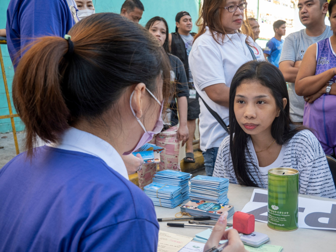 A Tzu Chi Youth assists a resident during the distribution of relief goods for fire victims of Barangay 330 in Sta. Cruz, Manila. 【Photo by Matt Serrano】