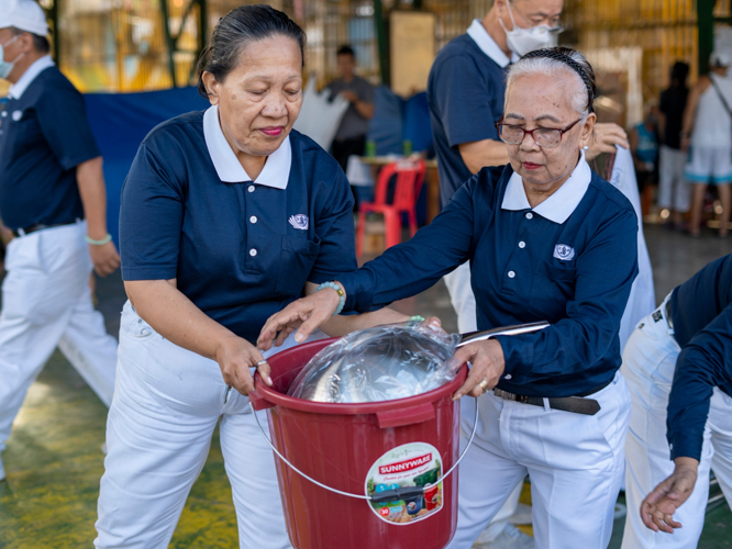 Tzu Chi volunteers work together as they transfer the relief goods into the covered court at Brgy. Tumana, where the beneficiaries for the fire relief are currently residing. 【Photo by Matt Serrano】