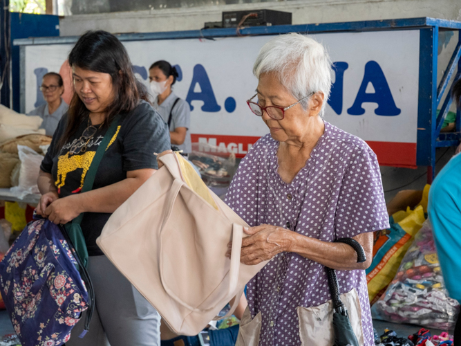 A customer inspects a bag inside and out before buying. 【Photo by Matt Serrano】