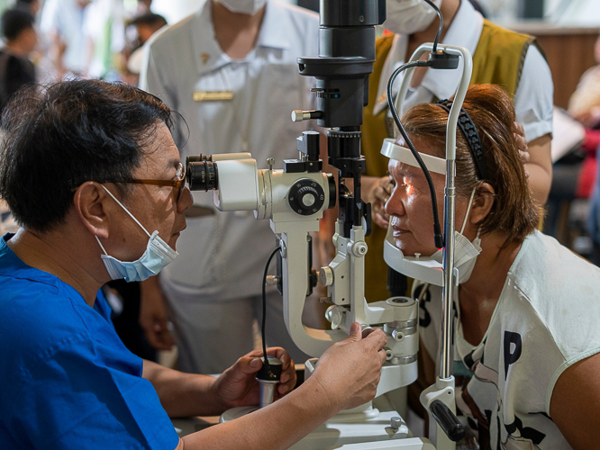The medical mission’s lone ophthalmologist Dr. Remegio Magan (left) checks a patient’s eyes.【Photo by Harold Alzaga】