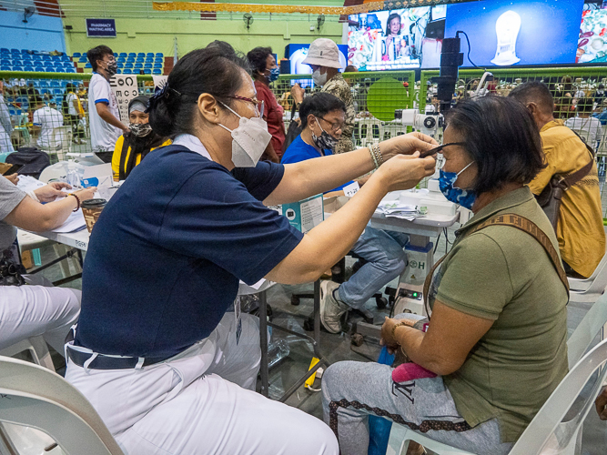 A Tzu Chi volunteer assists a patient in securing a pair of reading glasses.【Photo by Matt Serrano】