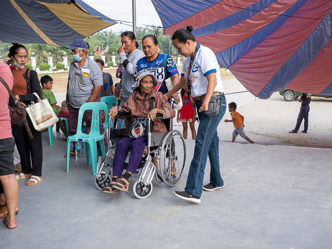 Nene assists a senior citizen at the waiting area of the medical mission. 【Photo by Matt Serrano】