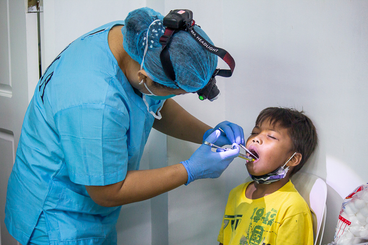A volunteer dentist administers anesthesia on a young patient before his extraction.【Photo by Marella Saldonido】