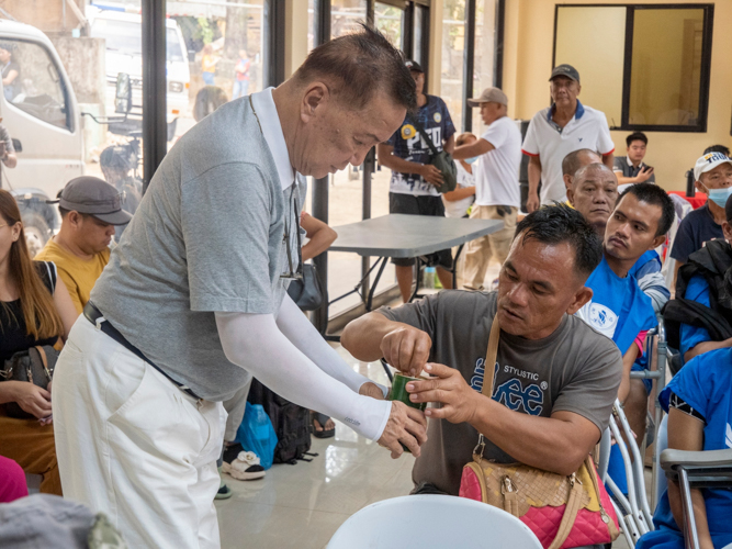 A companion of the prosthesis recipient puts his donations in the coin can.
