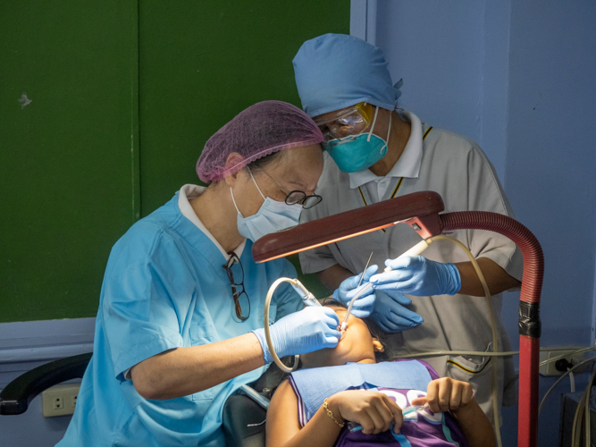 Volunteer dentists carefully examine the teeth of a child patient.