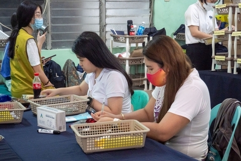Volunteers help in checking the prescription and medicine placed in baskets at the pharmacy area.