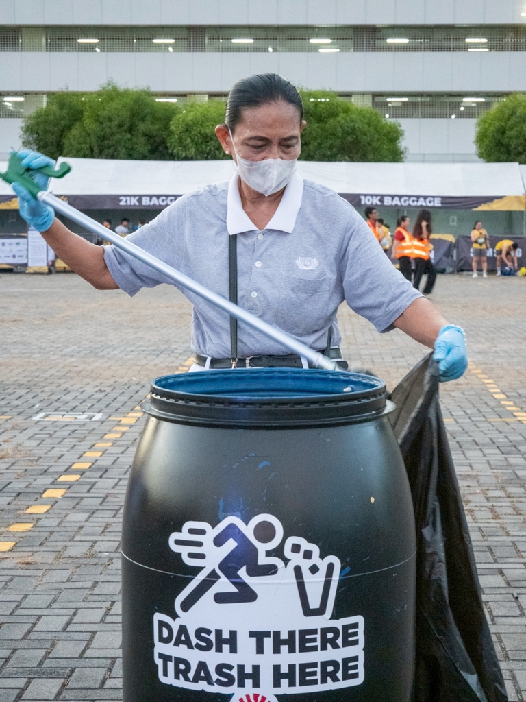 A volunteer uses thongs to collect trash from designated bins placed around the race village. 