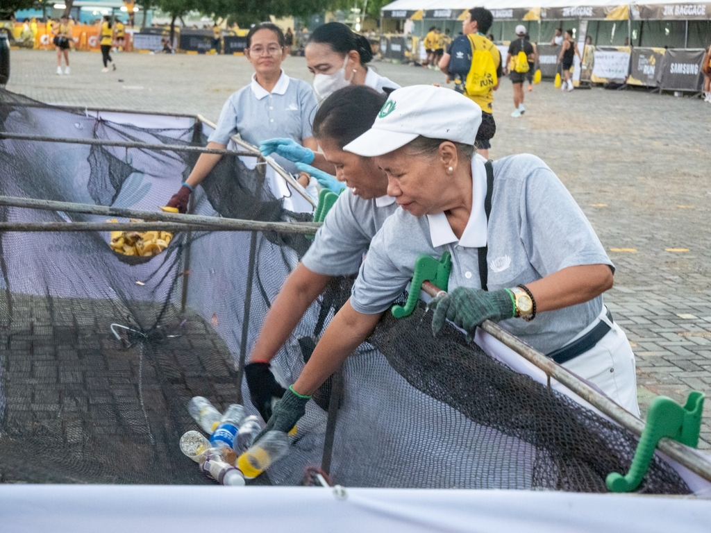 Volunteers reach for discarded PET bottles and banana peels at segregated trash stations. 