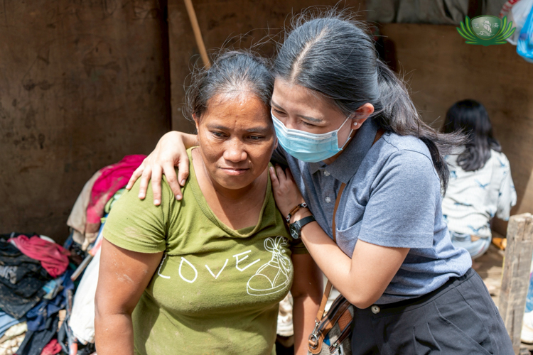 A staff member comforts Lorina Caño (left) with a hug.