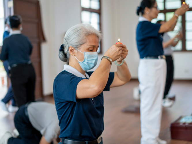 Levy Yao lights a candle and kneels in prayer inside the Jing Si Abode. 【Photo by Harold Alzaga】