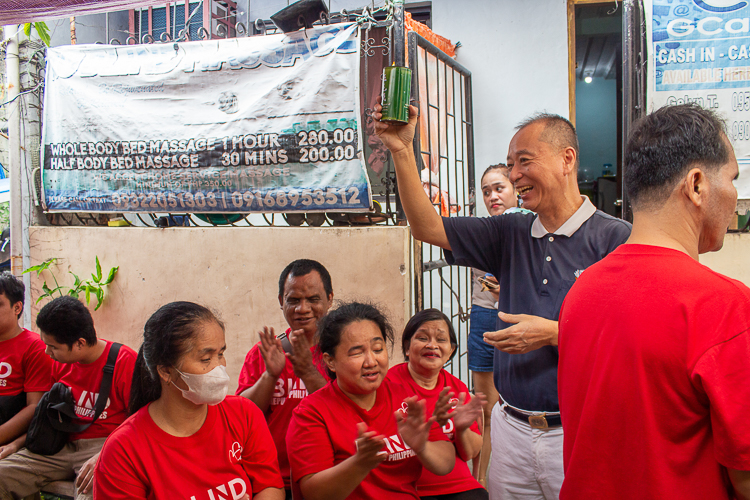 Tzu Chi volunteer Luis Diamante holds the donated coin bank with a big smile.  【Photo by Marella Saldonido】