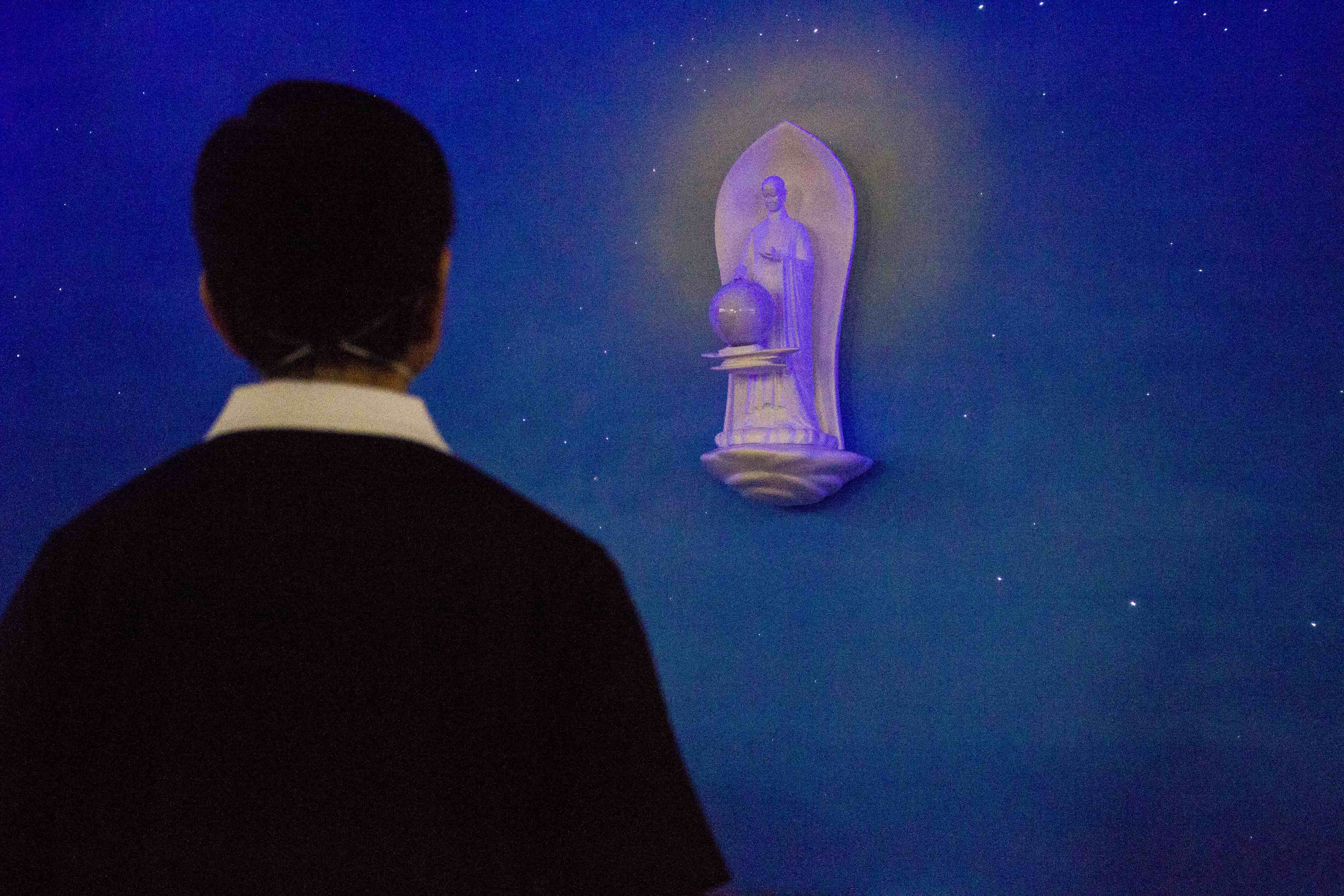 A volunteer admires the statue of Buddha amidst a reproduction of a starry night sky at the Jing Si Hall. 【Photo by Matt Serrano】