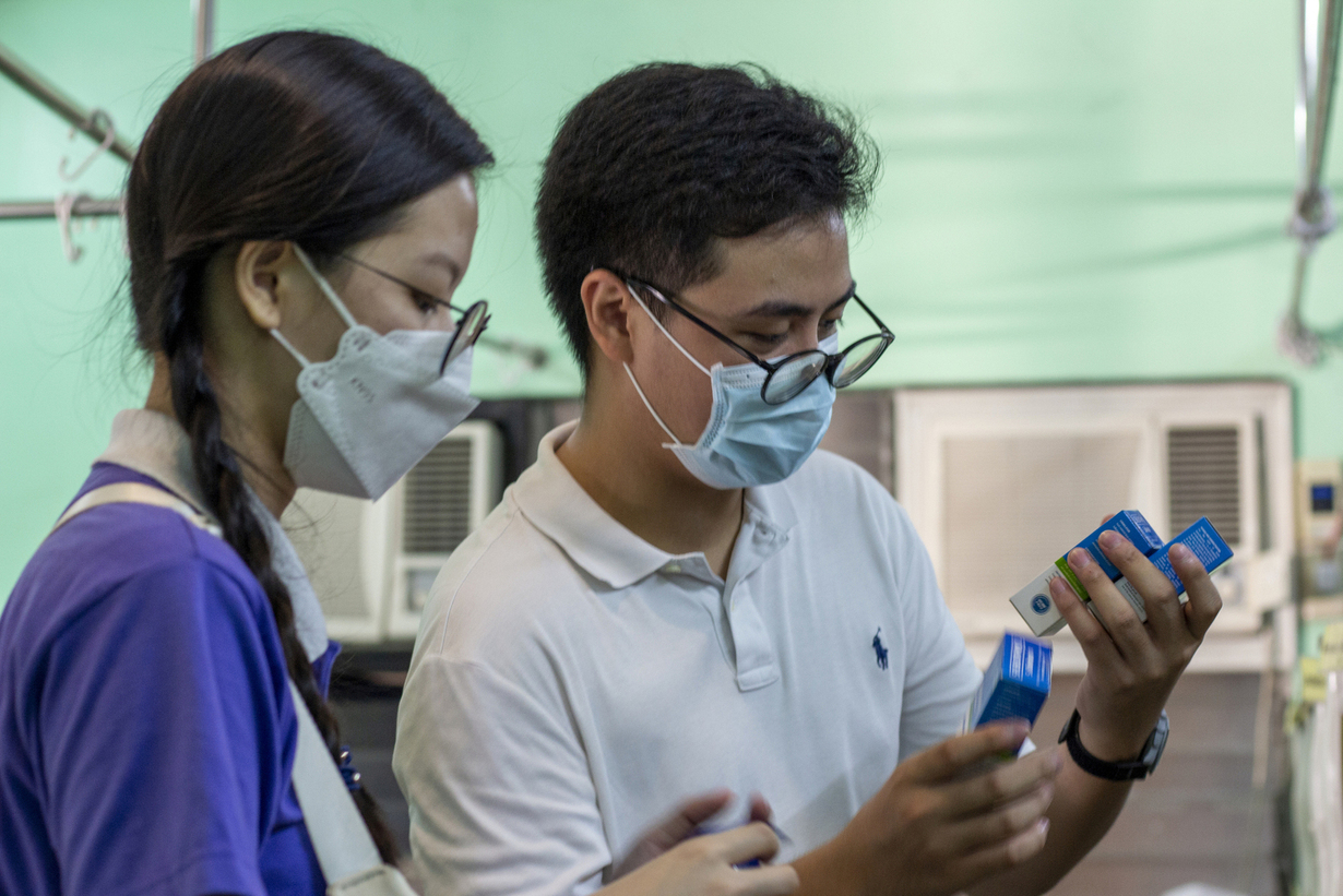 Volunteer medical student Vince Vitug (right) checks the prescription medicines for the patients.