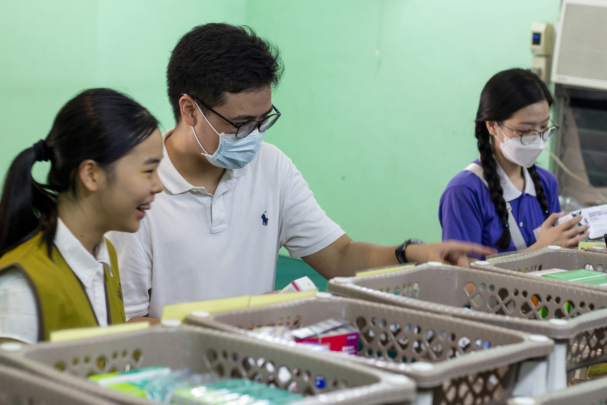 Together with fellow volunteers, Vince Vitug (center) collects the medicine indicated in the patients’ prescriptions.