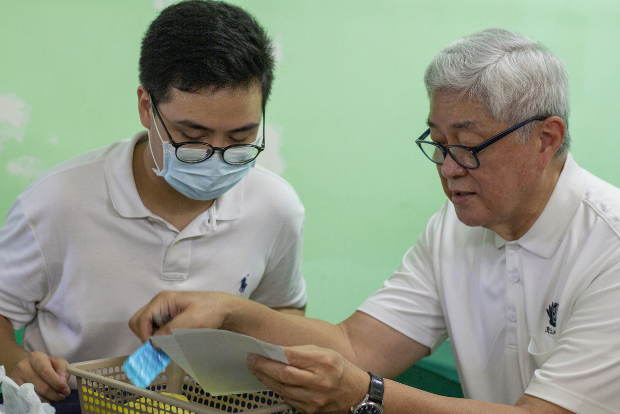 TIMA Doctor Josefino Qua (right) discusses prescriptions and medicines placed in a basket with Vince Vitug (left).