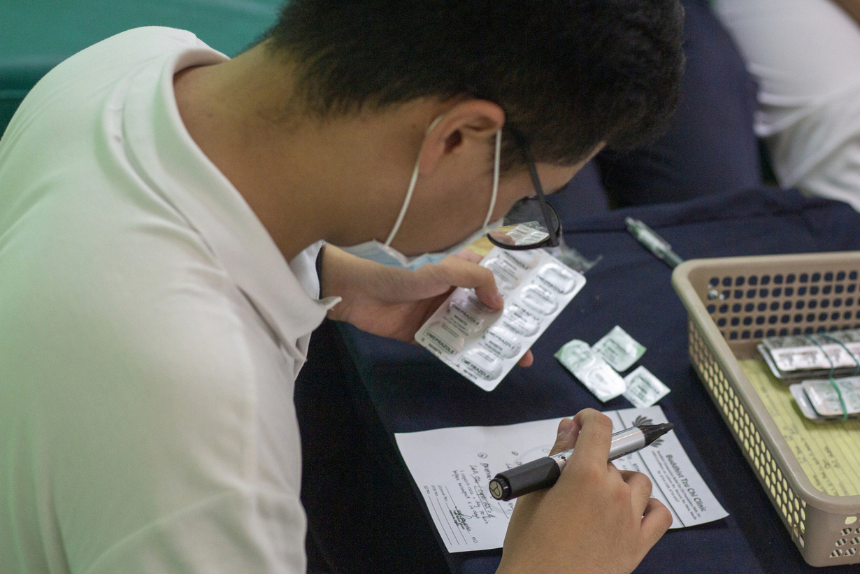 Volunteer medical student Vince Vitug helps in cross-checking prescriptions and medicines, ensuring patient safety at the medical mission.