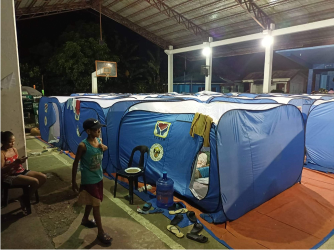Families wait out the storm in collapsible evacuation tents set up at a basketball court in Ormoc. 