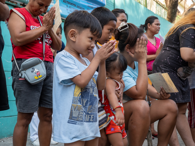 A little boy joins residents and Tzu Chi volunteers in prayer. 【Photo by Matt Serrano】