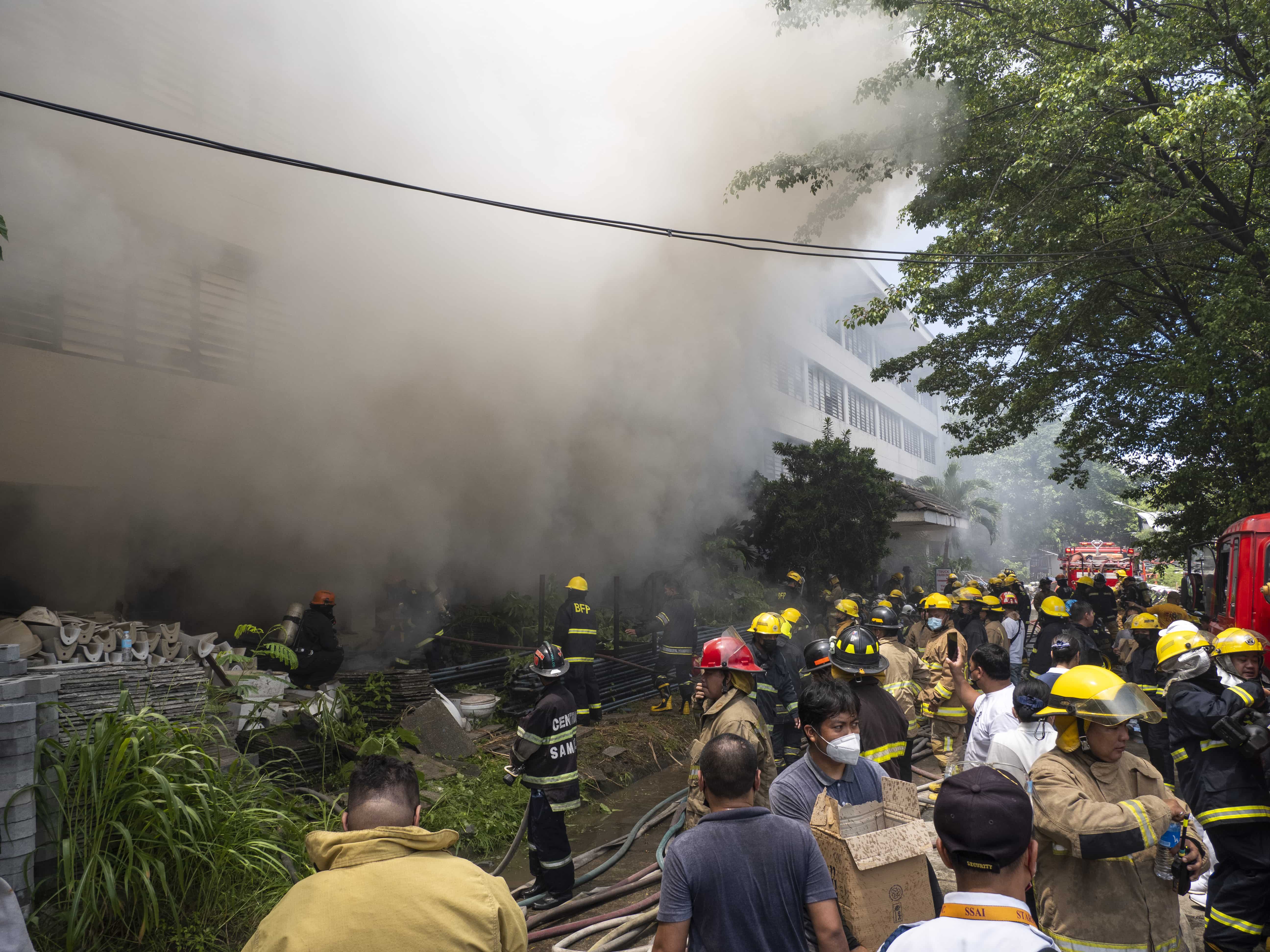 Firefighters and volunteers outside the burning building. 【Photo by Harold Alzaga】