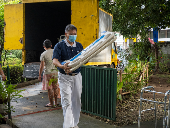 Tzu Chi volunteer Loreto Balete carries hospital bed frames. 【Photo by Matt Serrano】