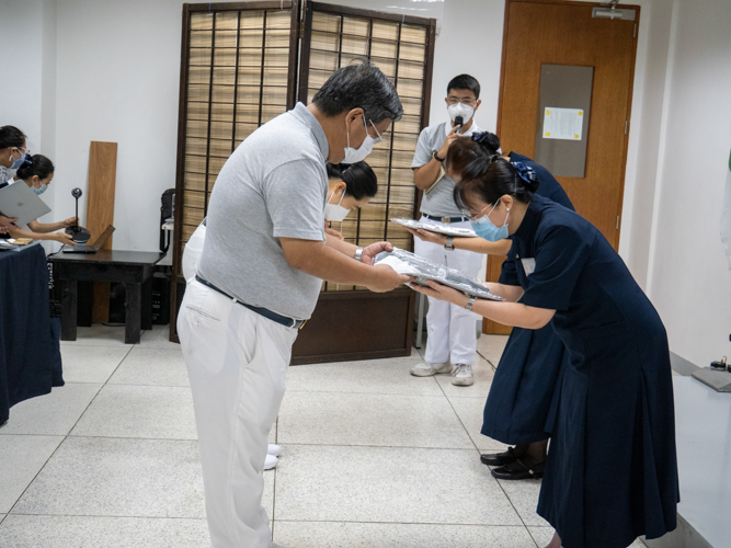 Volunteers bow as commissioners present them with their official volunteer uniform. 【Photo by Matt Serrano】