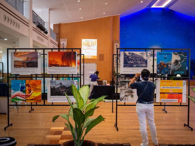 A Tzu Chi volunteer takes a photo of envrionmental protection and climate change information posters in Jing Si Hall.【Photo by Daniel Lazar】