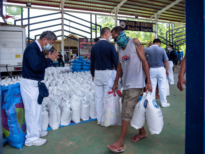 Recipient walking out with bag of rice and being greeted by Tzu Chi volunteer Johnny Kwok.【Photo by Daniel Lazar】