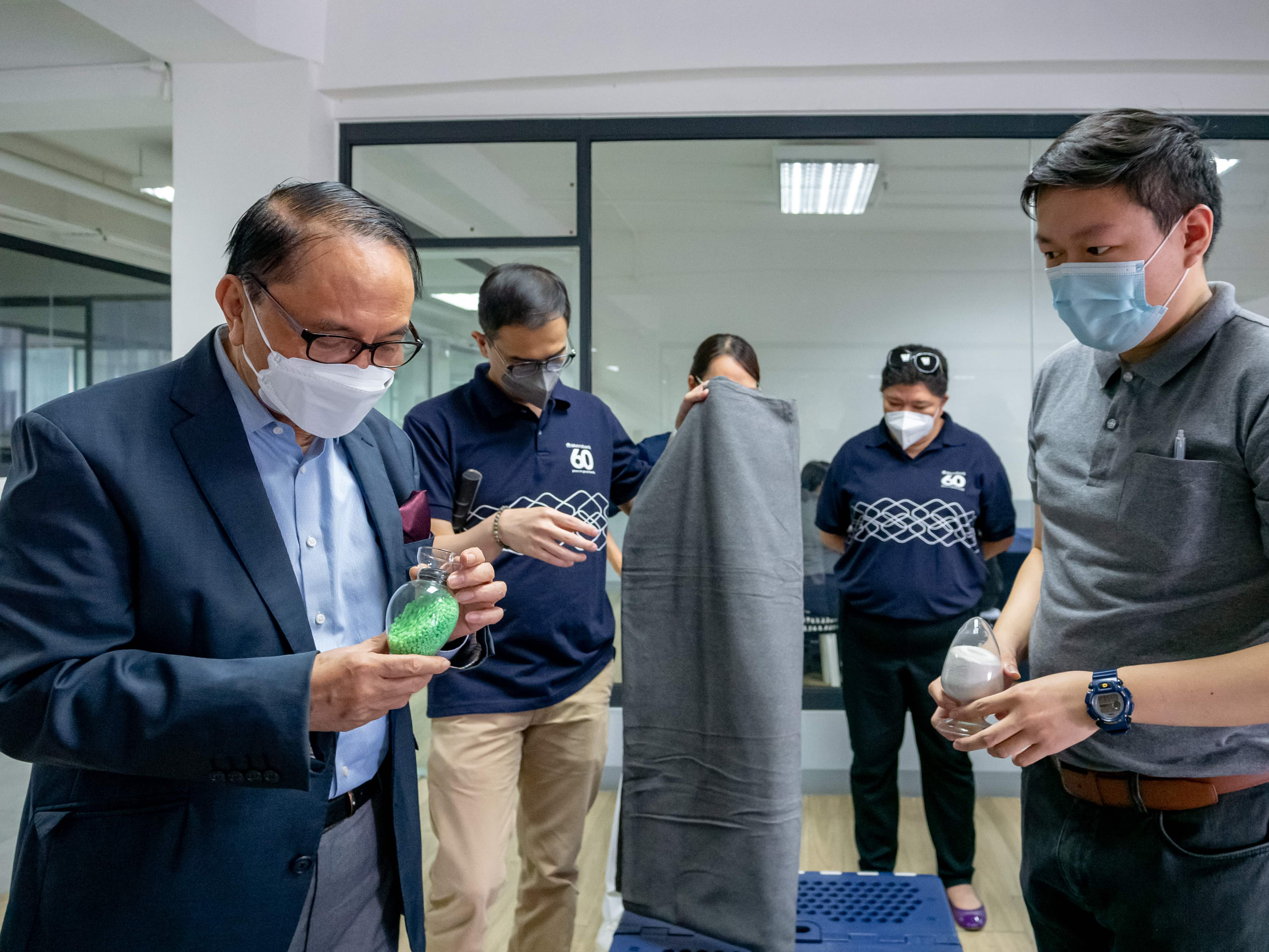 Mr. Chito Sobrepeña being shown blankets, and multi-function beds, made of recycled materials at Synergy Hall. 【Photo by Daniel Lazar】