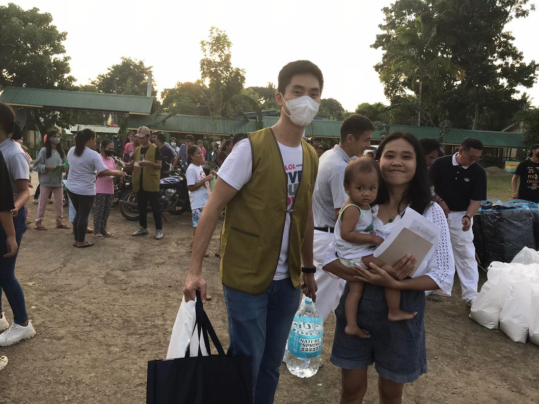 Volunteer Steven Ong helps a beneficiary carry her relief goods at Pasonanca Elementary School.