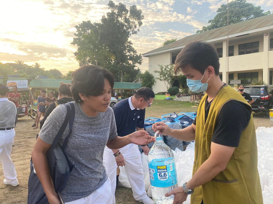 Volunteer Edison Yu distributes relief goods to a beneficiary at Pasonanca Elementary School.
