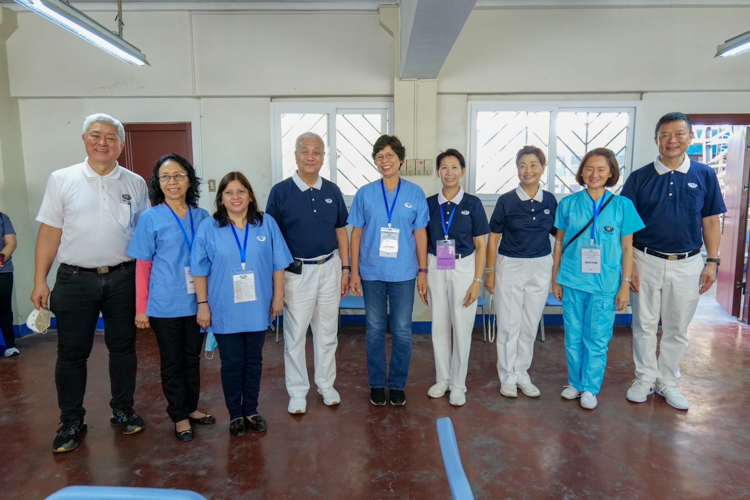 Volunteer doctors (in scrubs) are all smiles with TIMA and medical mission pioneer Dr. Jo Qua (first from left), Tzu Chi Philippines CEO Henry Yuñez (fourth from left), Tzu Chi Philippines Deputy CEO Woon Ng (sixth from left), Tzu Chi commissioner Molita Chua (third from right) and Tzu Chi Davao Chapter OIC Nelson Chua (first from right).【Photo by Matt Serrano】