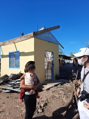 Surveying the extent of damages in Cebu caused by Super Typhoon Odette (Rai), Kinlon Fan (right) talks to a mother and child outside what’s left of a local chapel. 