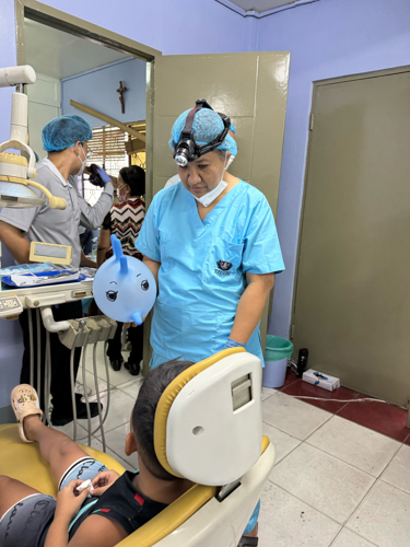 Dr. Rosa Fruto turns a rubber glove into an animal balloon to calm a young patient after a dental procedure. 