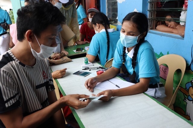 A typhoon victim receives her relief card from a Tzu Chi scholar.