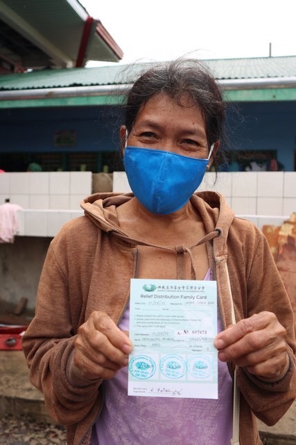 A beneficiary happily holds up her Tzu Chi relief card. 