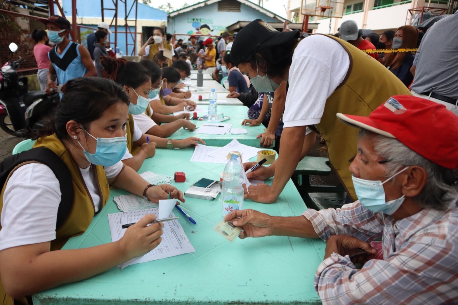 In Talisay, a volunteer assists a beneficiary in claiming his relief card.